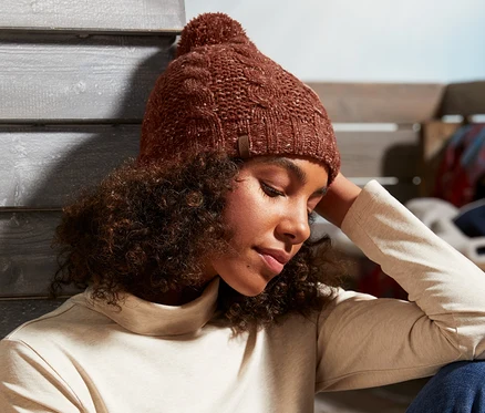 Une femme est assise et porte un bonnet en maille.