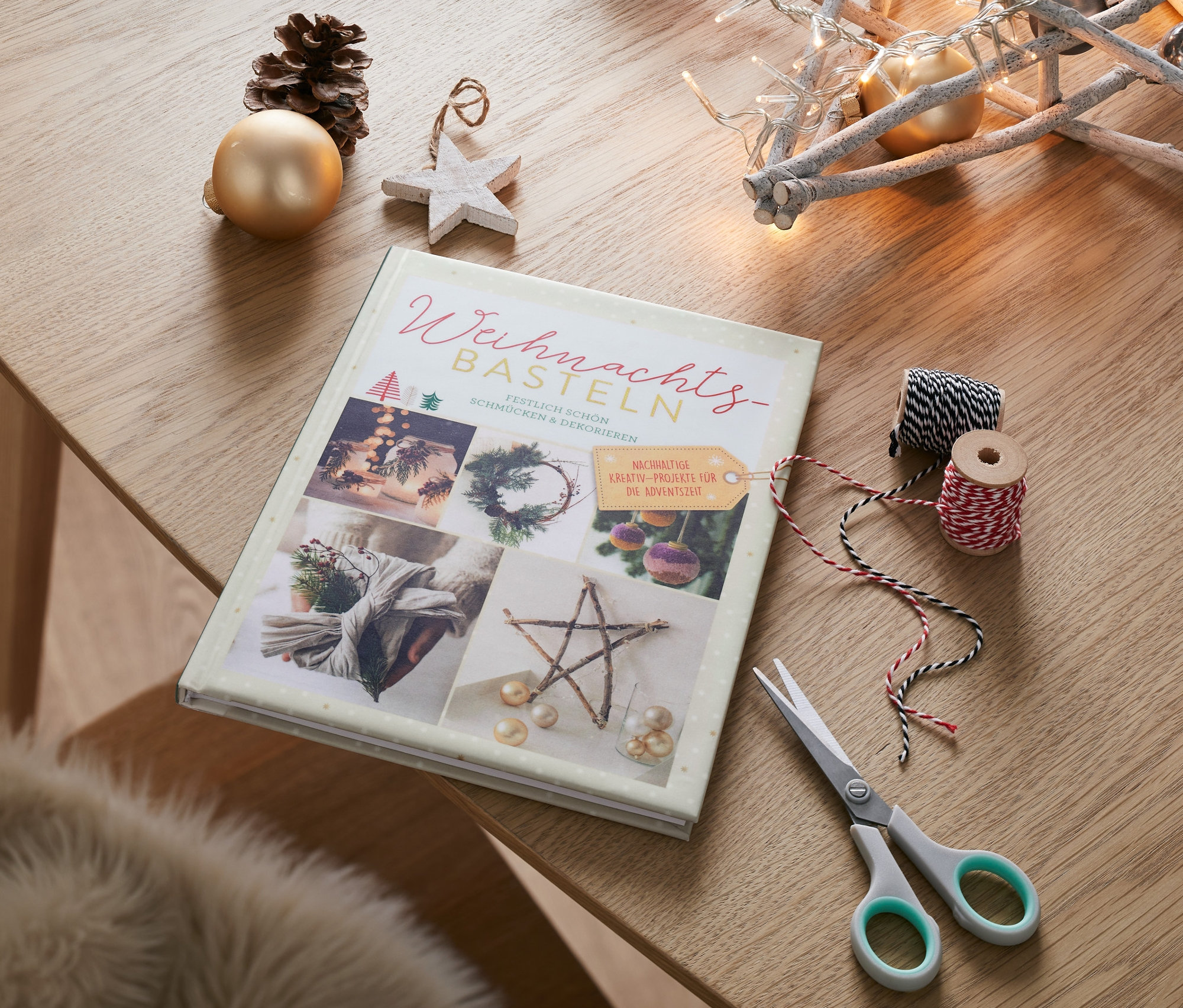 Le livre « Weihnachtsbasteln » (« Bricoler pour Noël ») est posé sur une table à côté de ciseaux, de ficelles et de décorations de Noël.