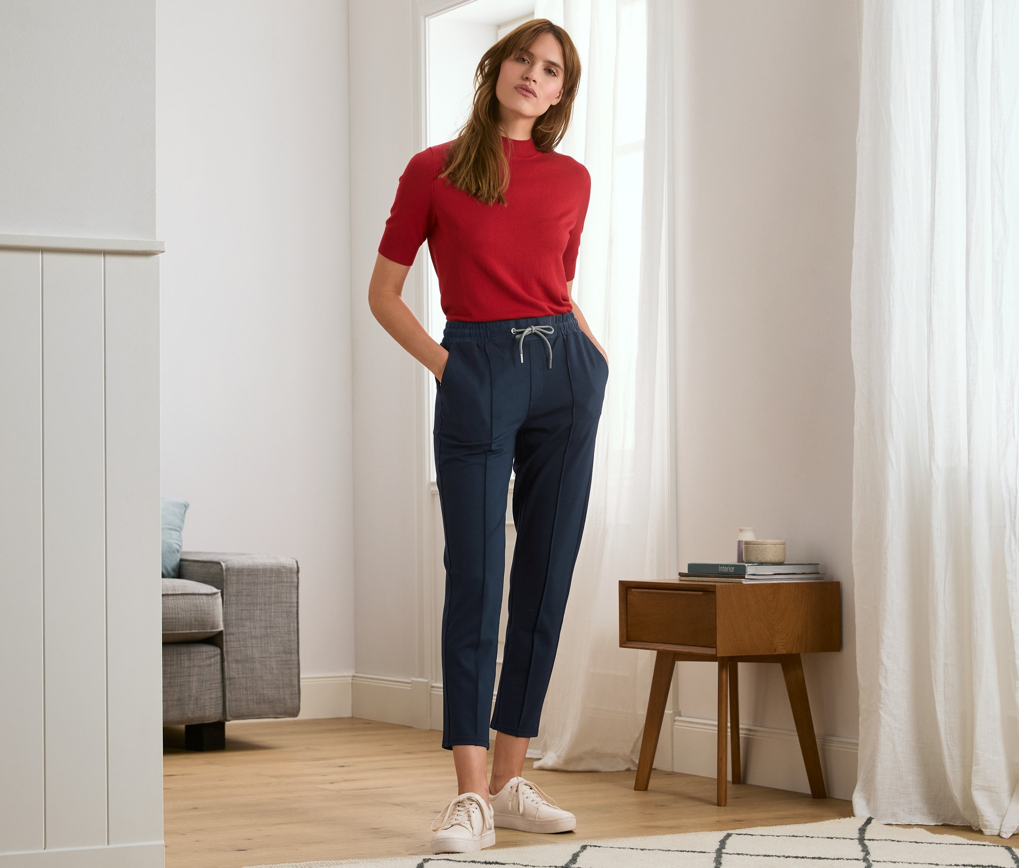Femme posant dans un haut rouge et un pantalon de jogging avec nervure.