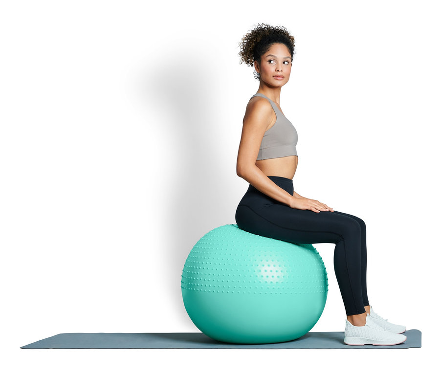 Femme assise sur une balle de gymnastique.