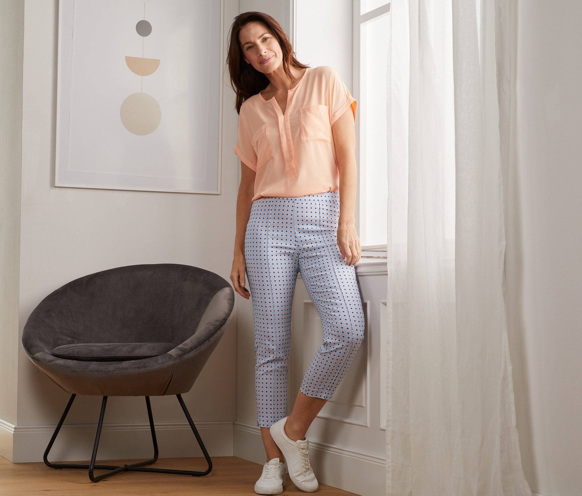 Femme posant près de la fenêtre, portant un pantalon stretch imprimé 7/8.