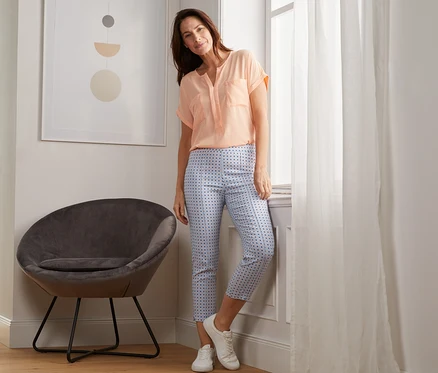 Femme posant près de la fenêtre, portant un pantalon stretch imprimé 7/8.