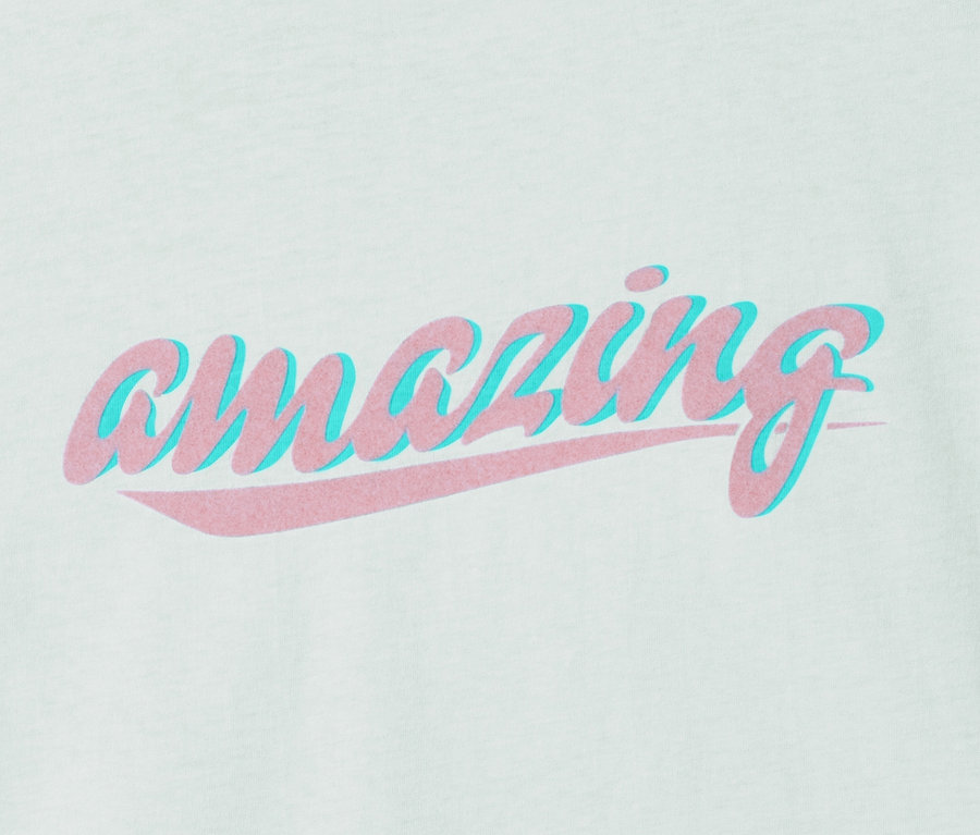 T-shirt vert clair en coton bio avec l'inscription rose « amazing » et une ombre bleue.