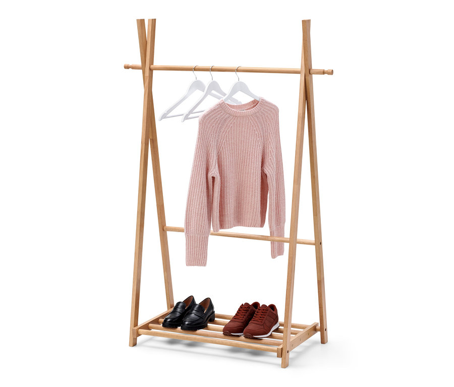 Un pull est suspendu à deux cintres blancs sur une tringle à vêtements en bois massif. Sur l'étagère inférieure, il y a des mocassins noirs et des baskets marron.