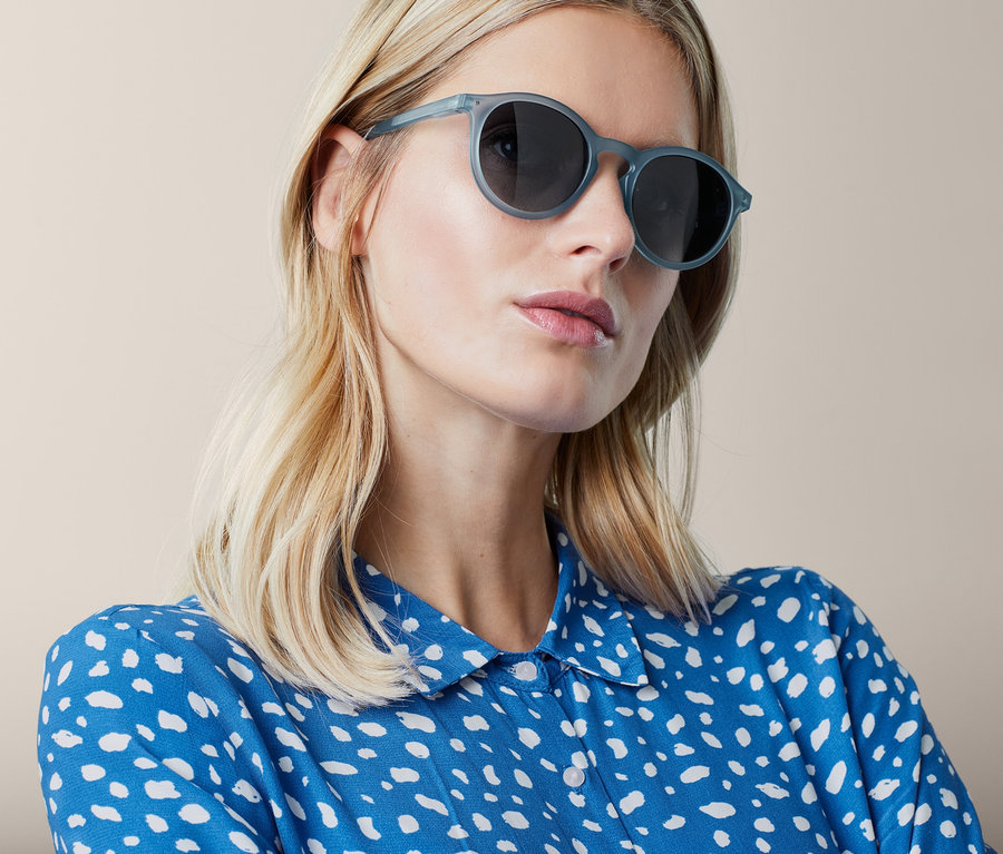 Une femme blonde porte des lunettes de soleil bleu clair.