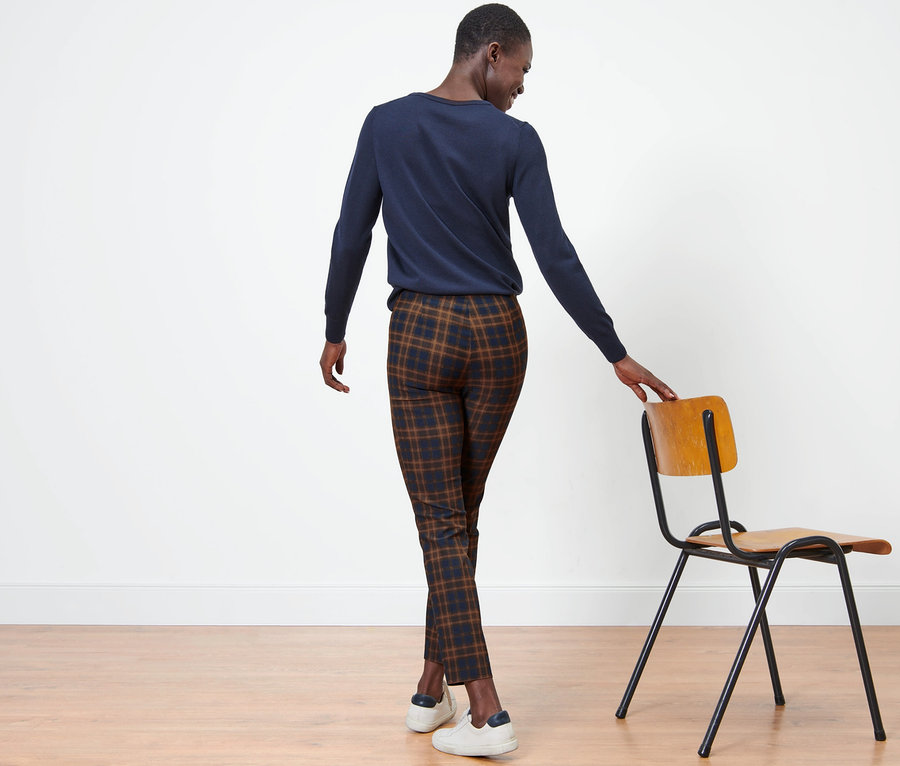 Une femme, vue de dos, porte un pantalon stretch à carreaux.