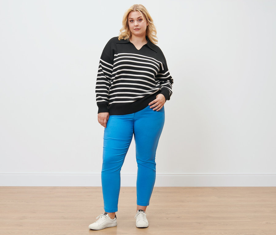 Une femme pose avec un pull avec col et un pantalon en bengaline.