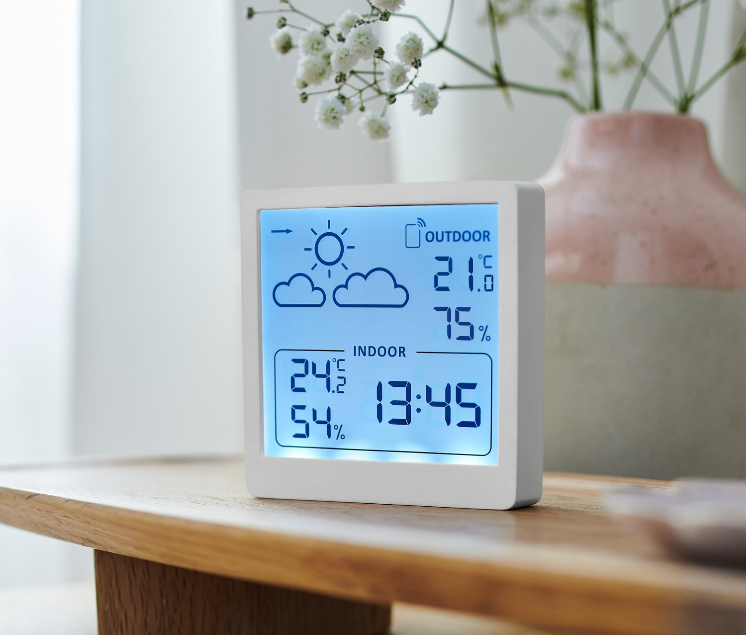Une station météo blanche affiche la température intérieure et extérieure et l'humidité.