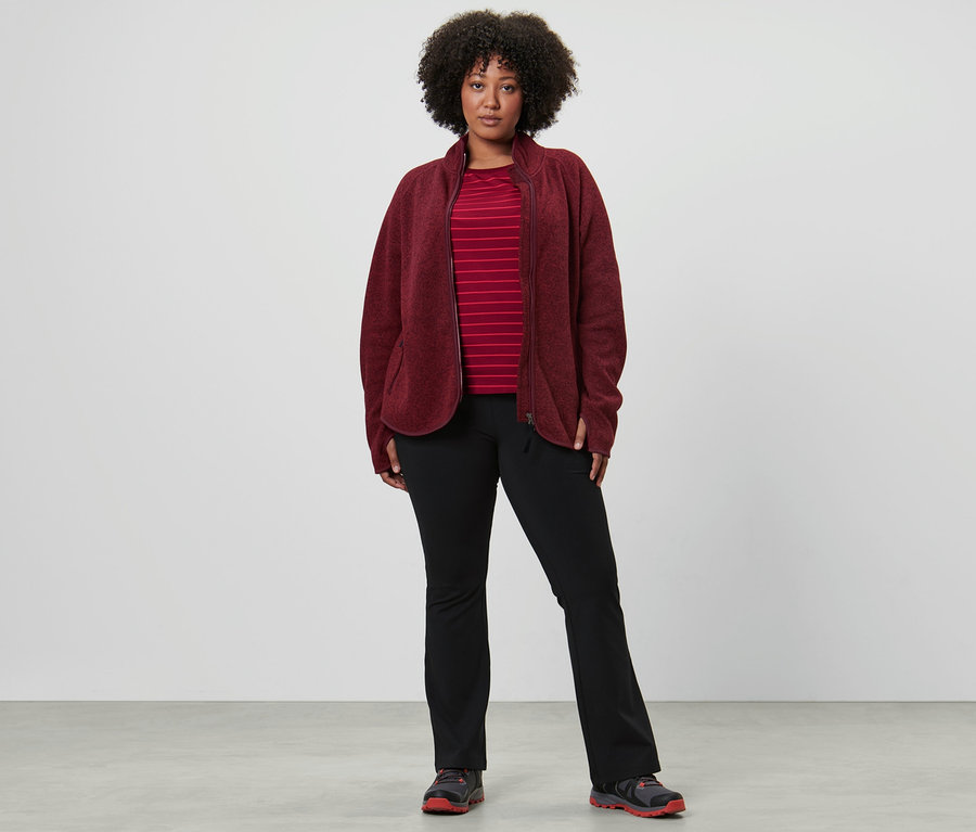 Une femme portant un t-shirt de sport manches longues, un pantalon jazz thermique et une veste en maille polaire, rouge foncé.
