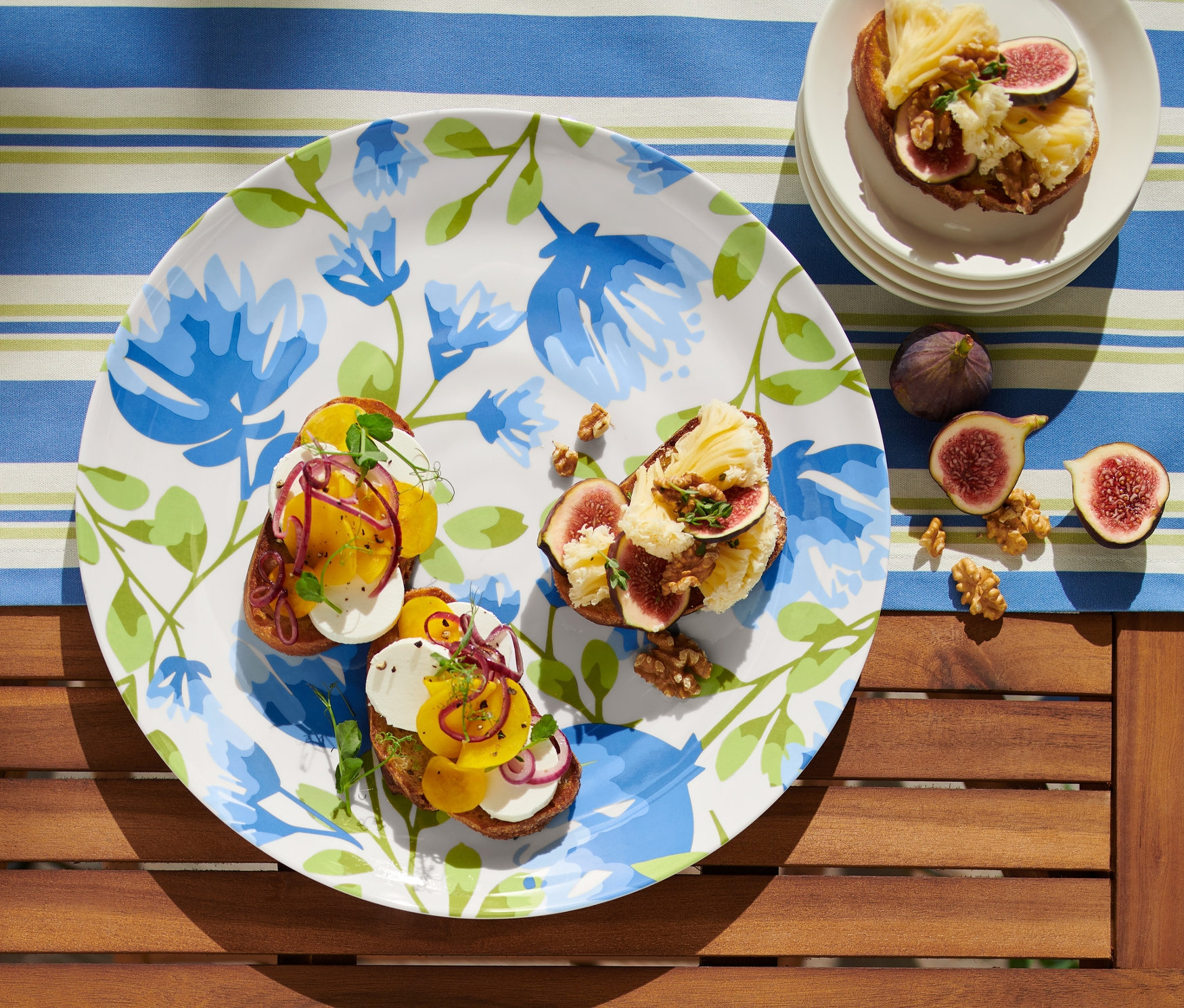 Un plat de service avec des tartines garnies et des figues est posé sur une table.