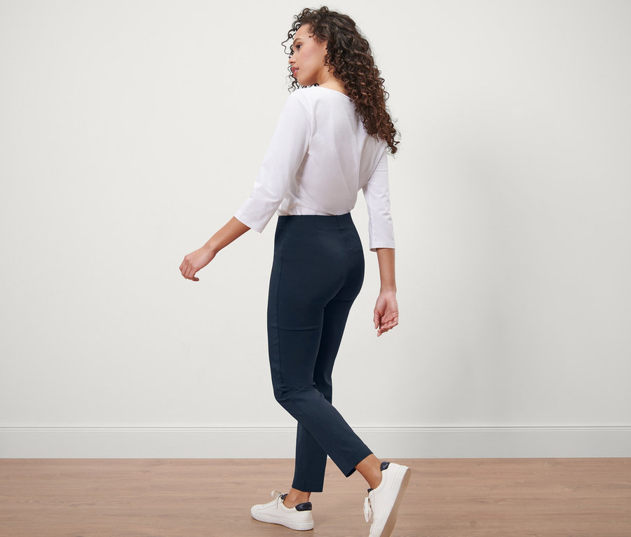 Femme marchant en pantalon stretch bleu foncé.