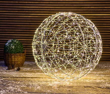 Une grande boule LED repose sur un plancher en bois recouvert de neige.