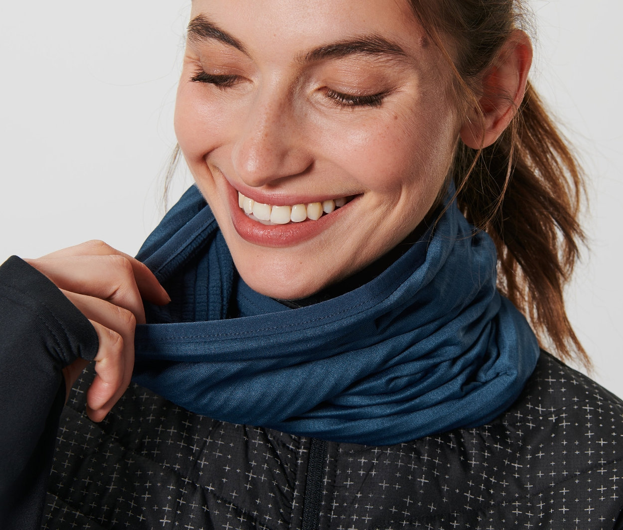 Femme ajustant un foulard multifonction bleu.