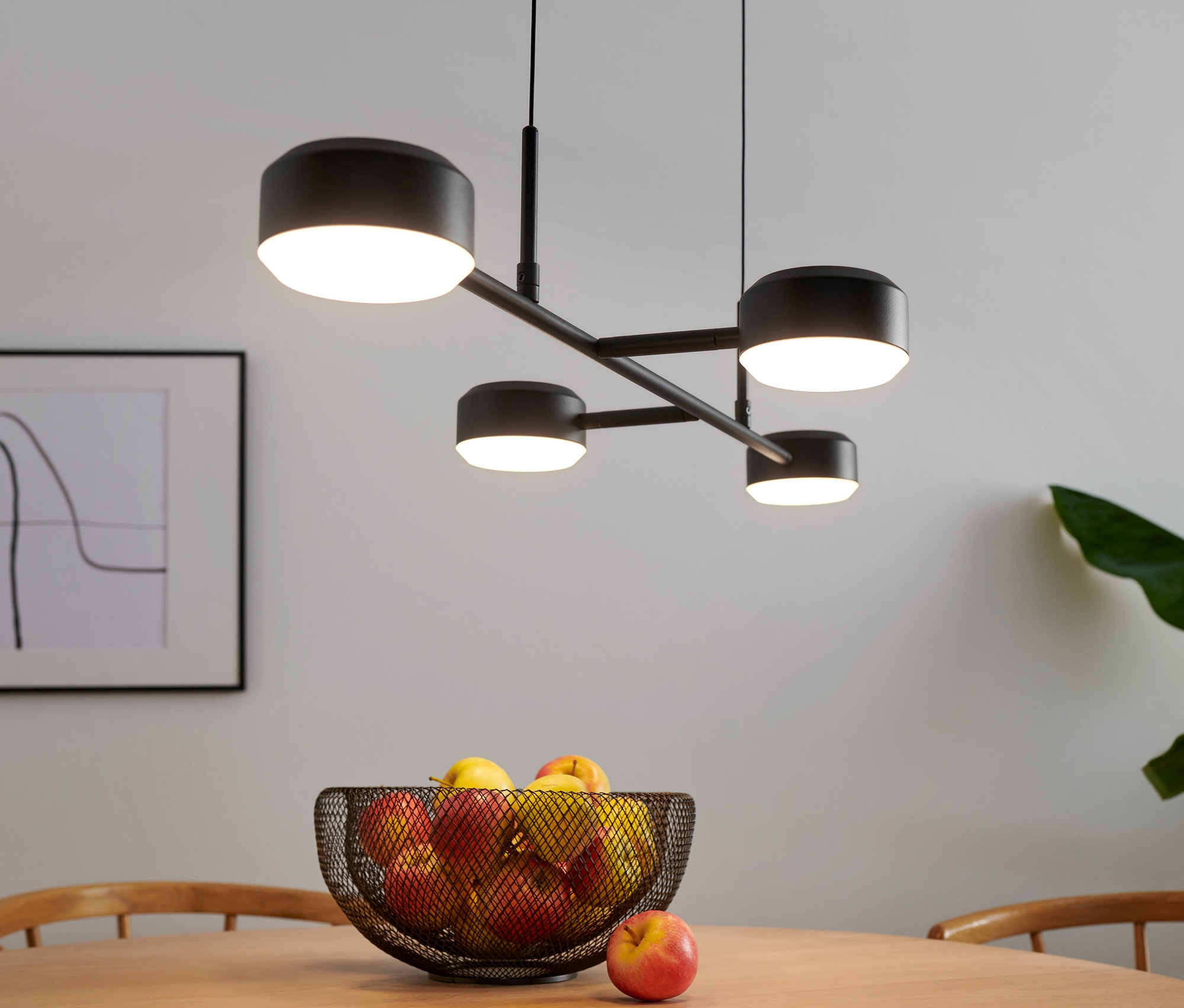 Lampe suspendue LED, 4 feux, au-dessus d'une table avec des fruits.
