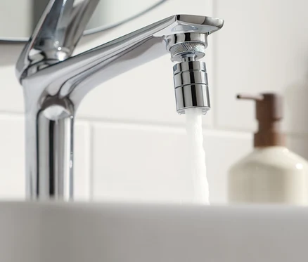 De l'eau coule d'un robinet avec un embout économiseur d'eau.