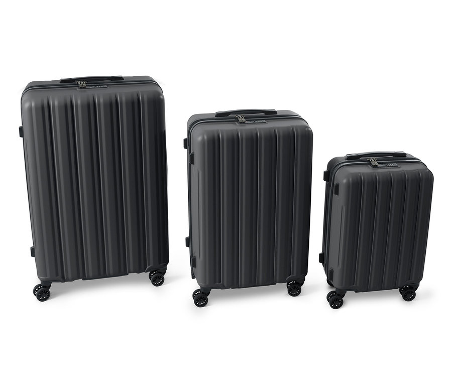 Trois valises rigides noires, moyennes, sont placées côte à côte.