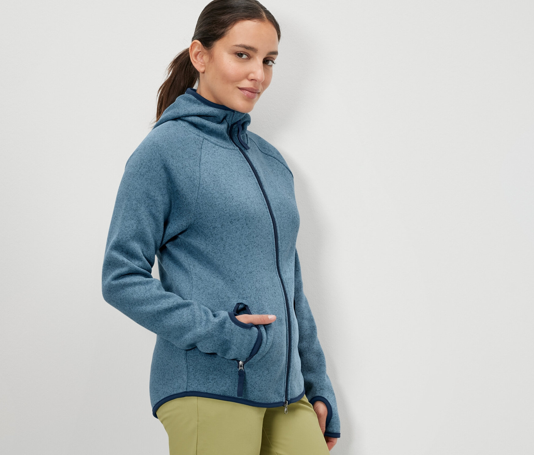 Femme posant en veste en polaire tricotée bleu foncé.