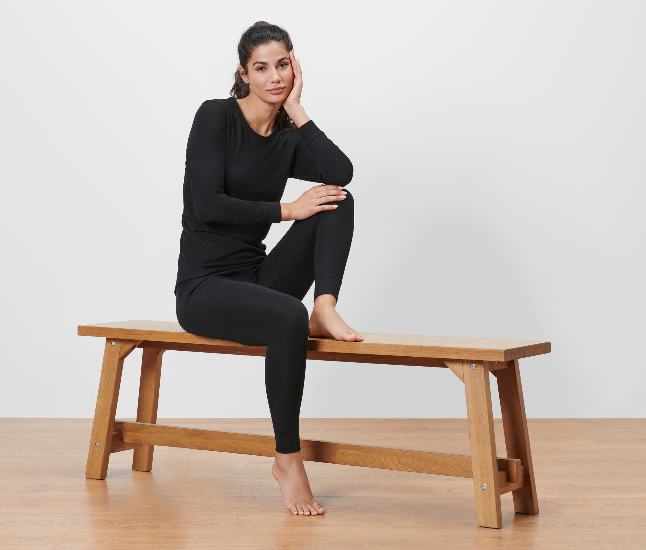 Femme assise sur un banc portant des sous-vêtements techniques thermiques noirs.