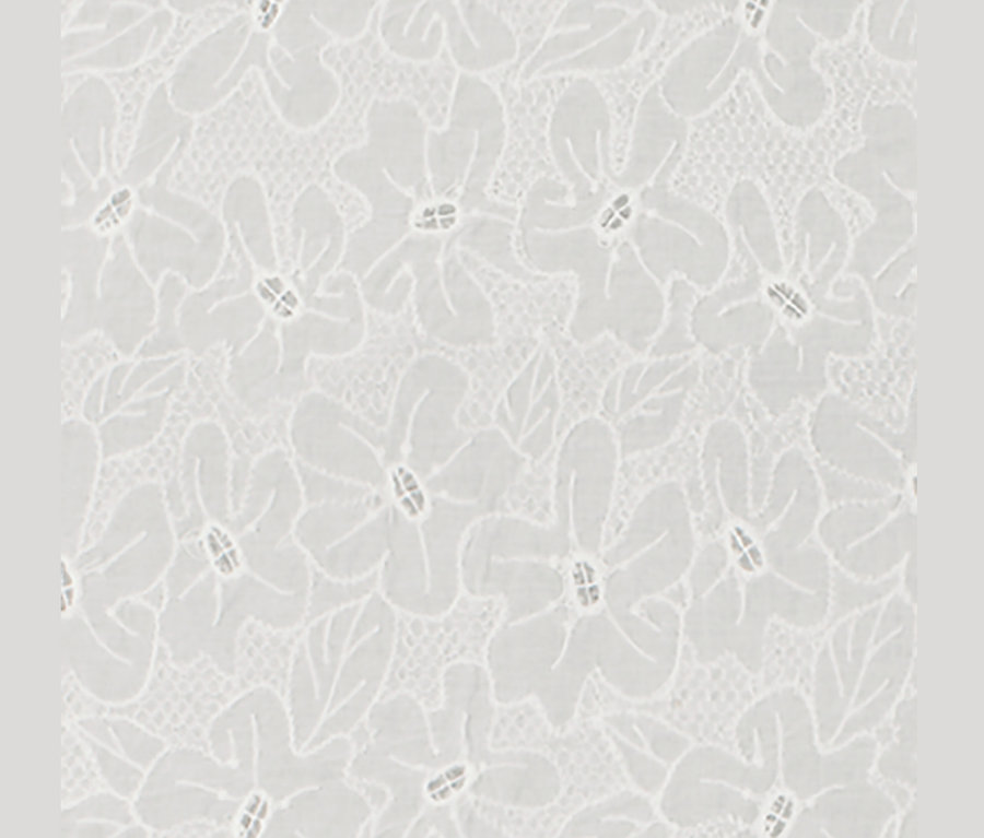 Détail d'une blouse blanche avec broderie florale.