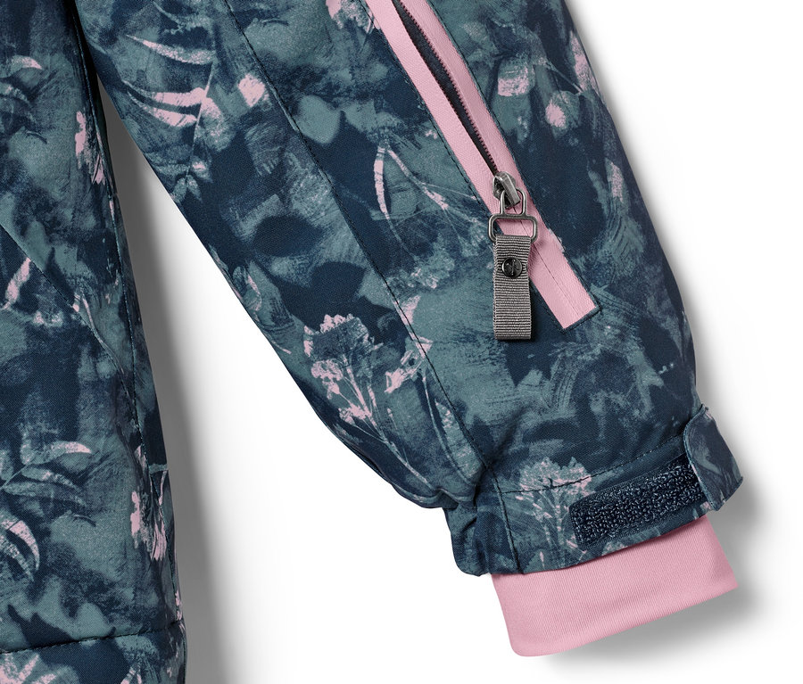 Détail d'une veste de ski pour enfant avec un motif floral et une fermeture éclair rose.