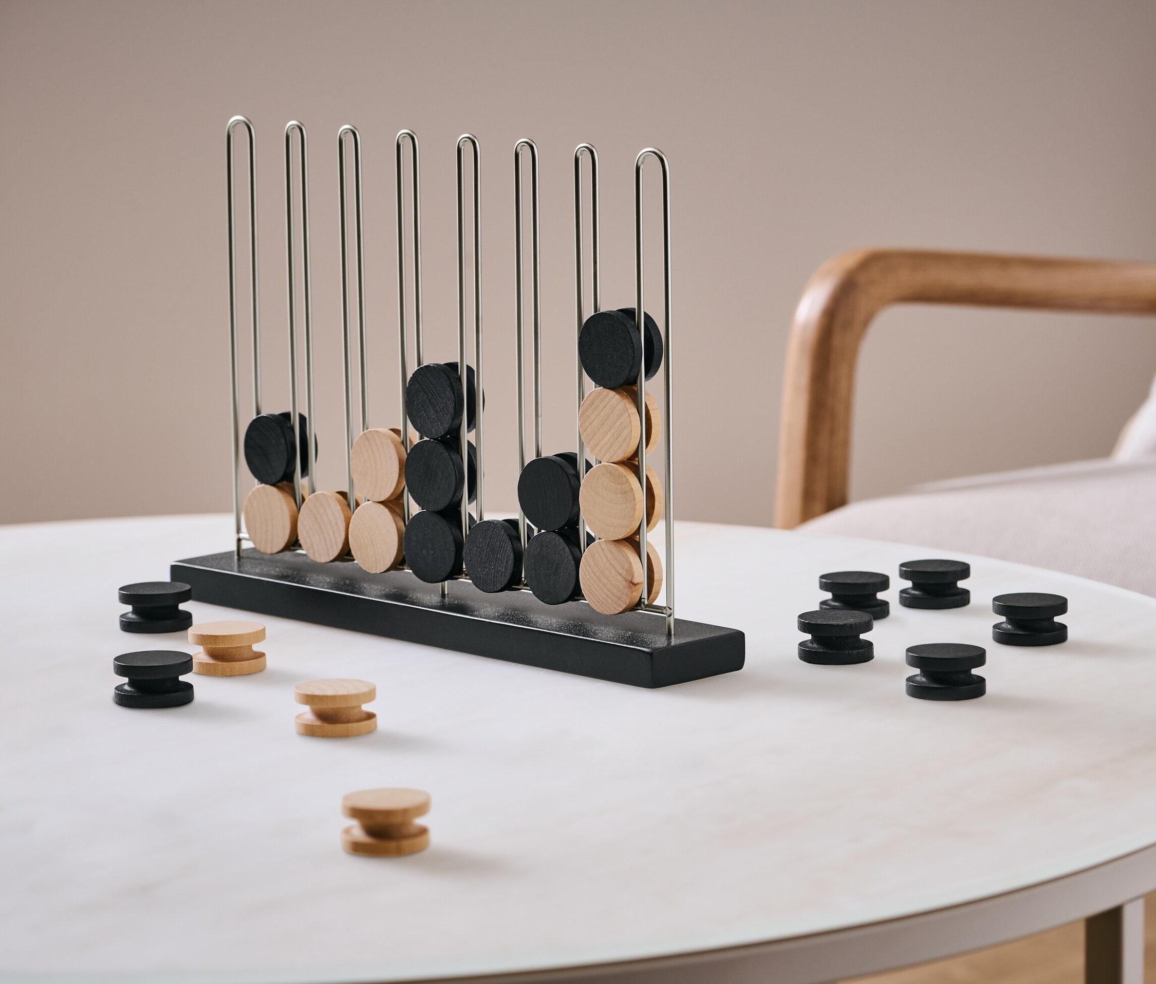 Jeu « 4 en ligne » avec jetons noirs et bois clair sur une table.
