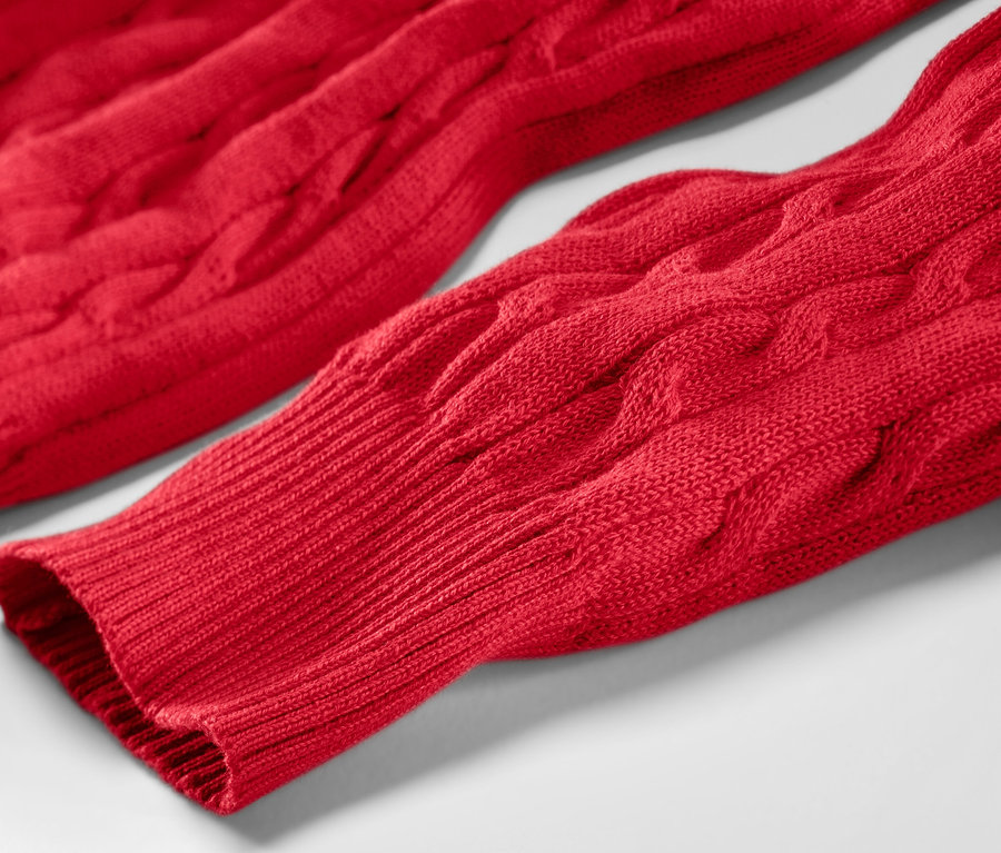 Gros plan sur un pull en maille torsadée rouge.
