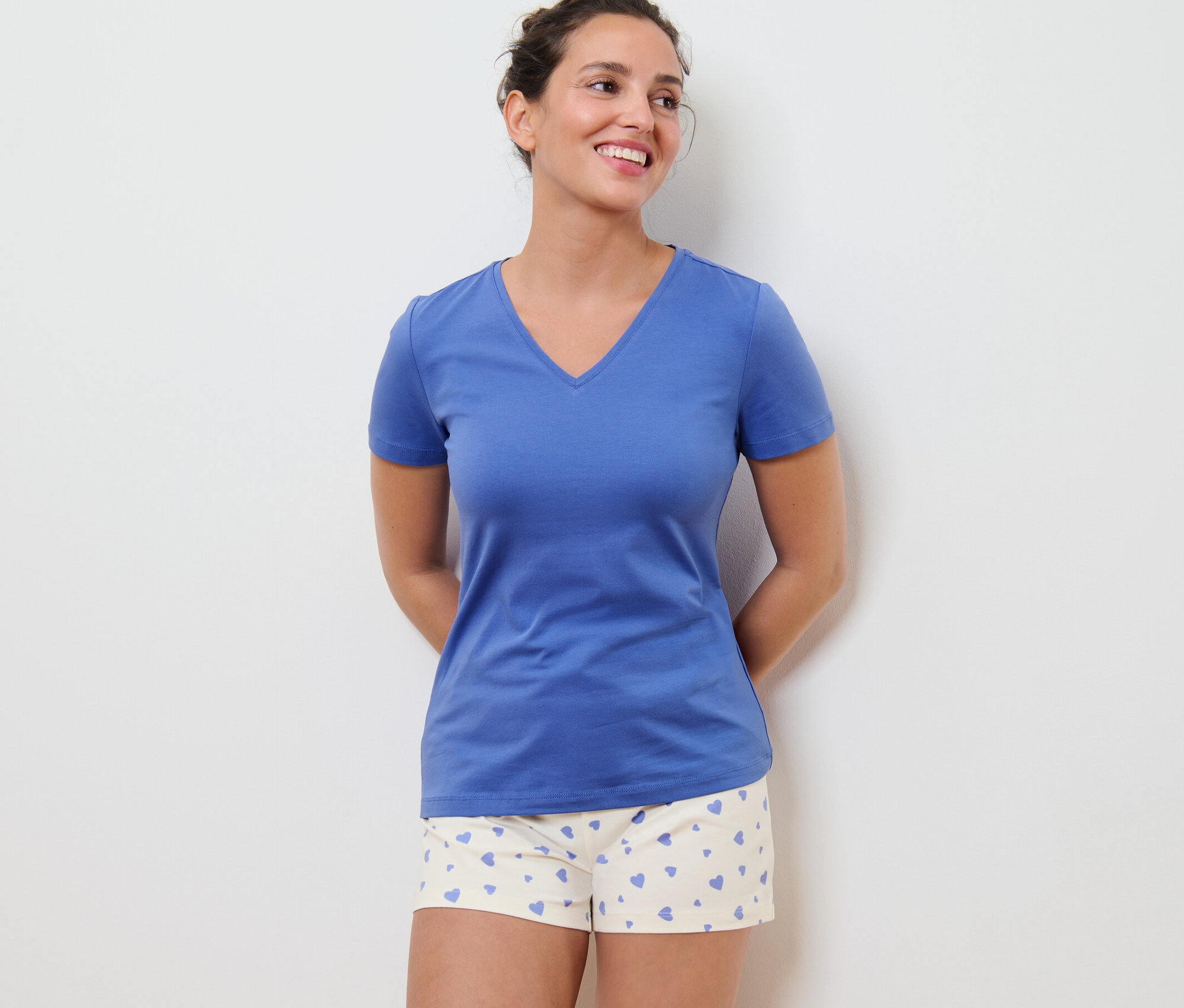 Une femme porte un pyjashort à cœurs et un t-shirt bleu.