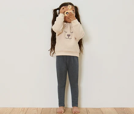 Fillette regardant à travers un appareil photo en bois et portant un legging thermique pour enfant gris.