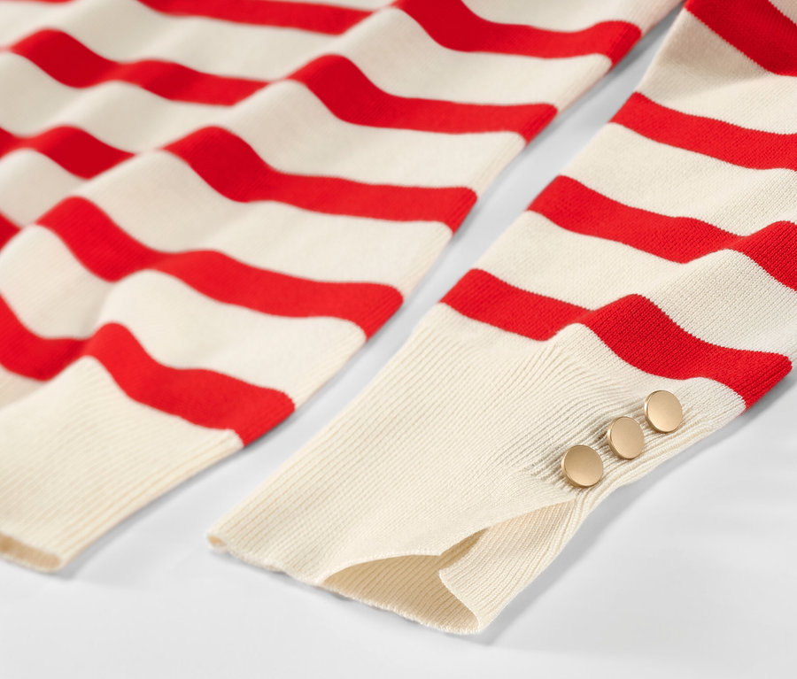Détail d'un pull en maille fine rayé rouge.