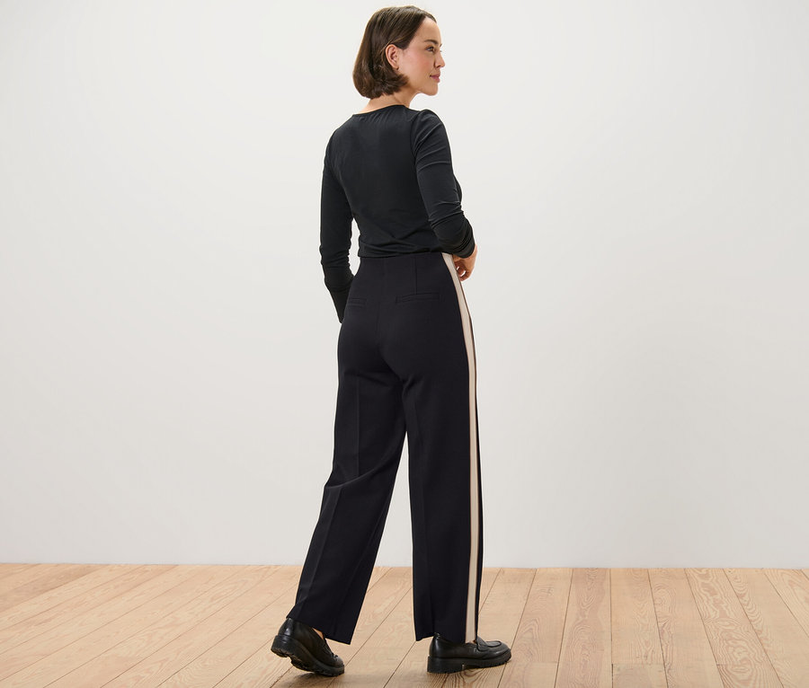 Femme portant un haut noir et un pantalon en jersey avec des bandes de galons.