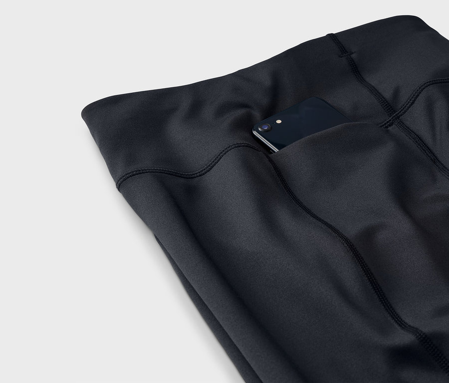 Gros plan d'un legging noir avec un smartphone dans la poche.