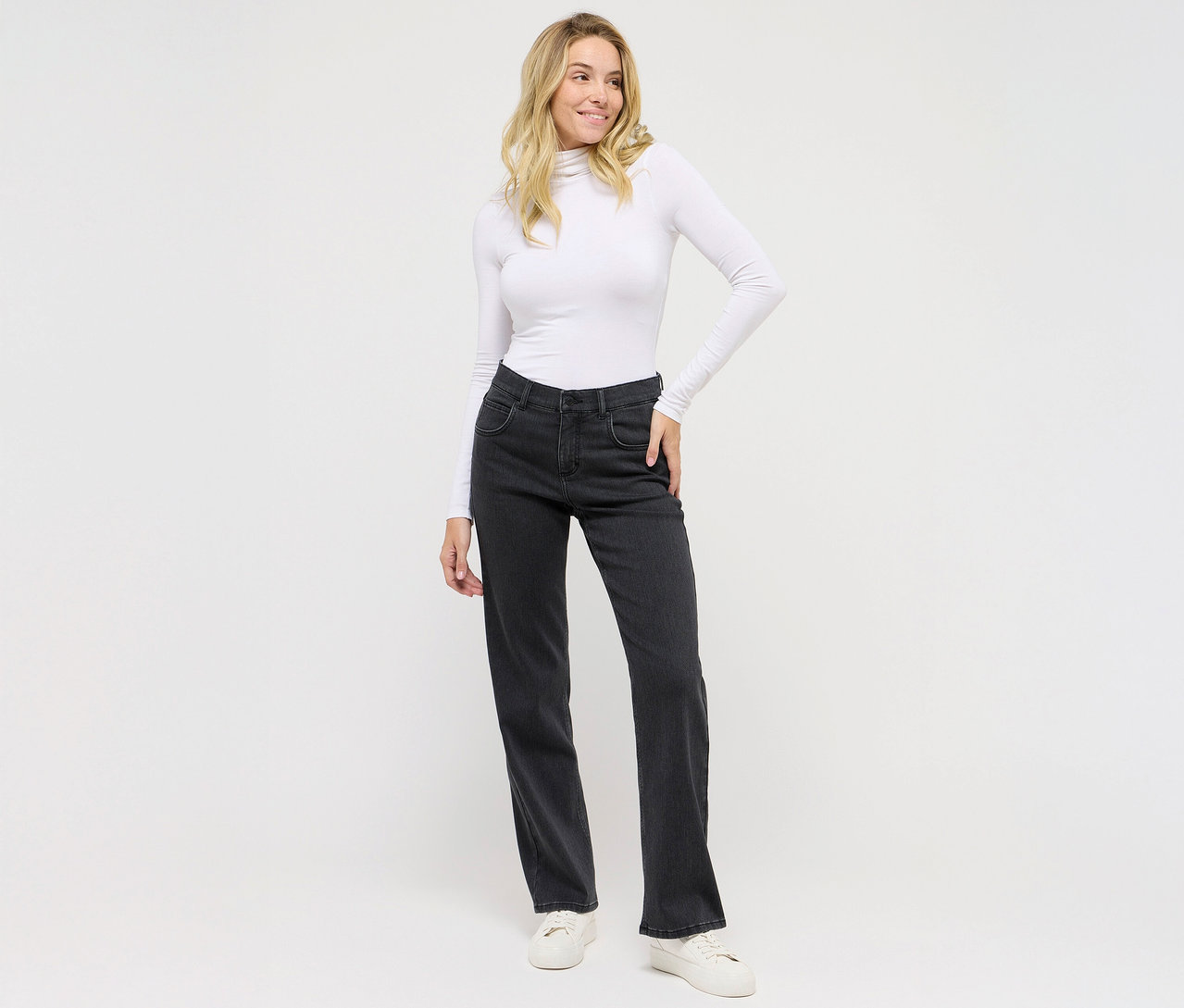 Femme posant en jean Angels Denim « Lara », coupe droite, gris foncé et haut blanc.