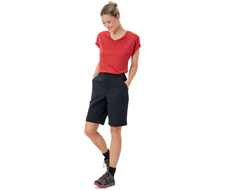 Femme debout avec les mains dans les poches d'un pantalon fonctionnel 2 en 1 noir.