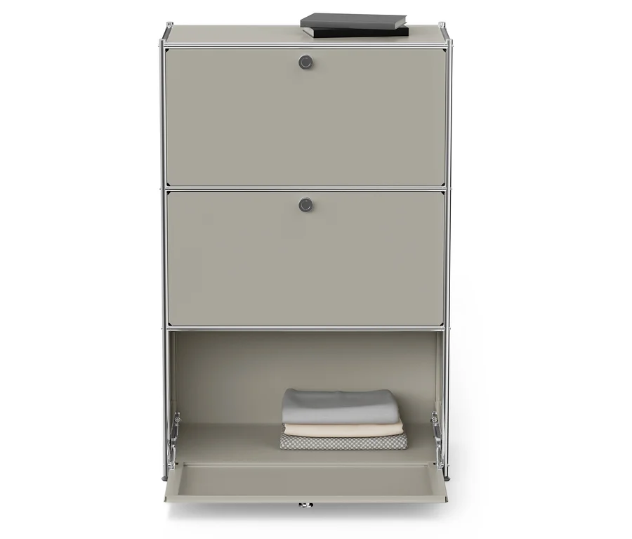 Armoire à trois étages avec un compartiment inférieur ouvert contenant des vêtements pliés et un livre posé sur l'armoire supérieure.