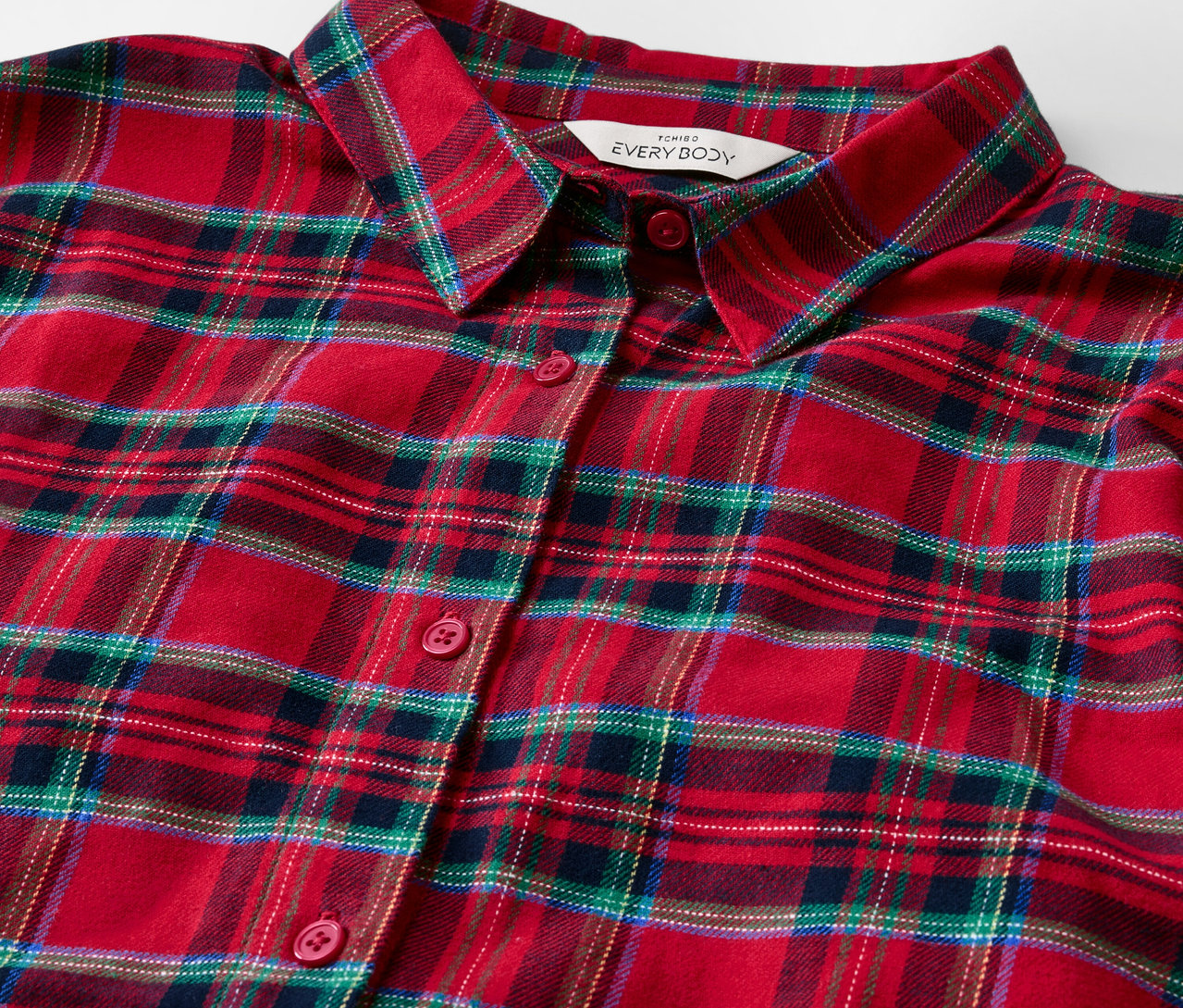 Gros plan sur une chemise à carreaux rouges avec un col et des boutons.