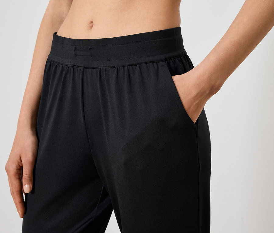 Une femme a sa main dans la poche d'un pantalon noir.