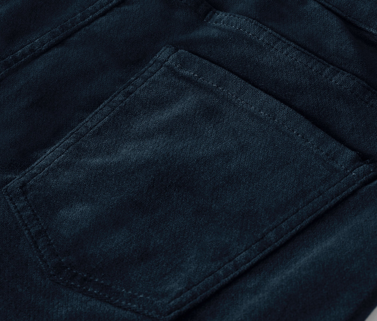 Détail de la poche arrière d'un pantalon en velours bleu foncé.