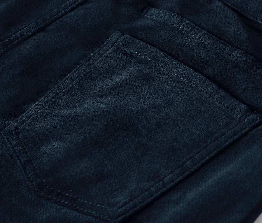 Détail de la poche arrière d'un pantalon en velours bleu foncé.