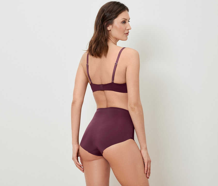 Femme posant en soutien-gorge et culotte bordeaux.