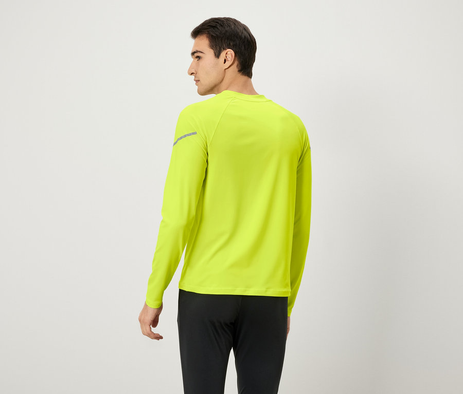 Homme de dos portant un t-shirt à manches longues jaune néon et un pantalon noir.