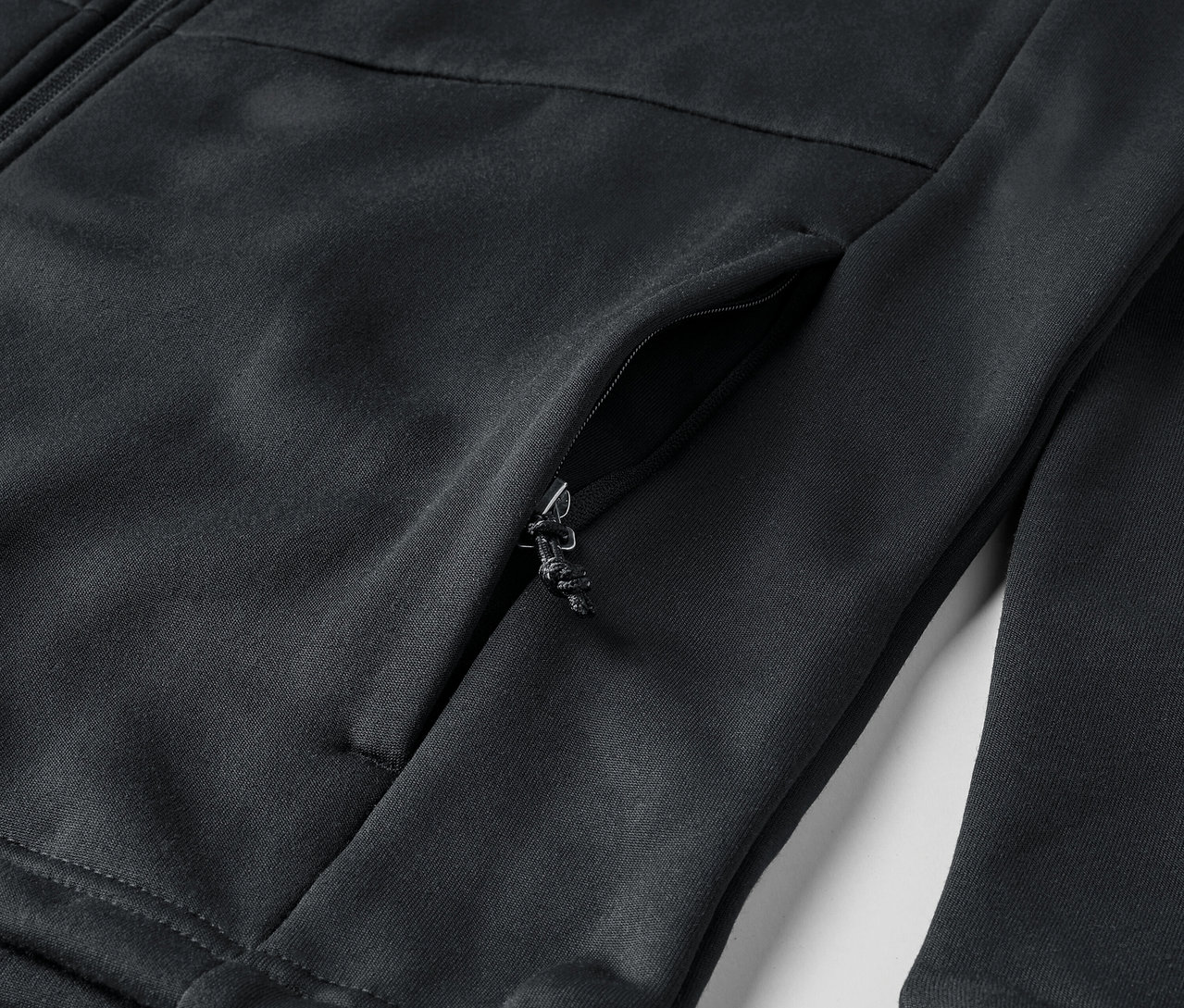 Gros plan sur une veste zippée noire avec une poche.