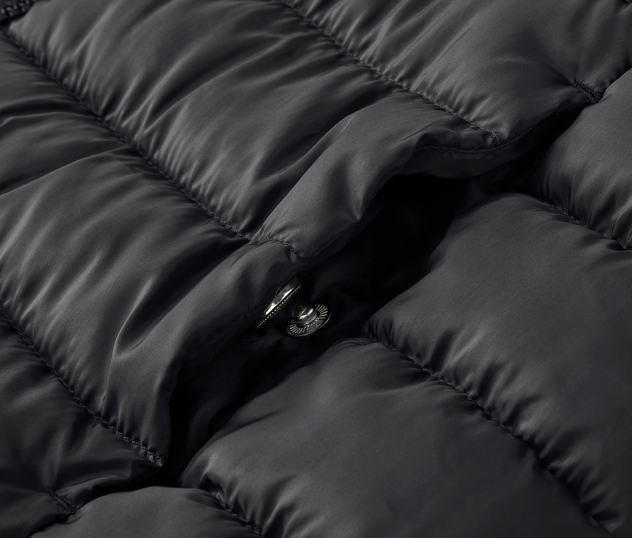 Gros plan d'une veste matelassée noire avec un bouton-pression.