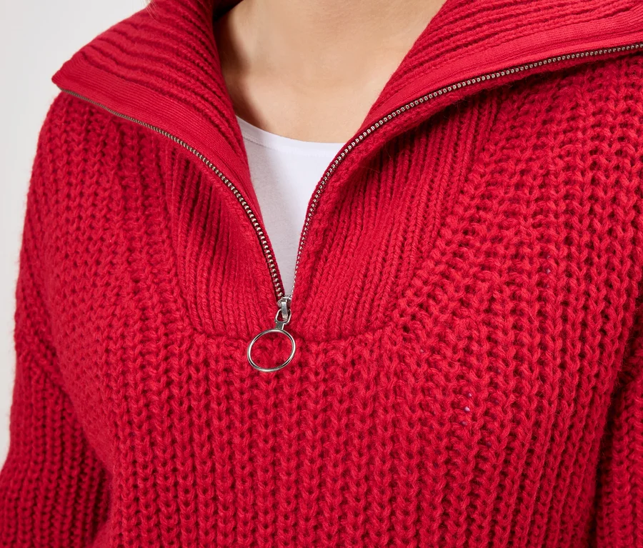 Gros plan d'un pull en tricot rouge avec un col zippé.