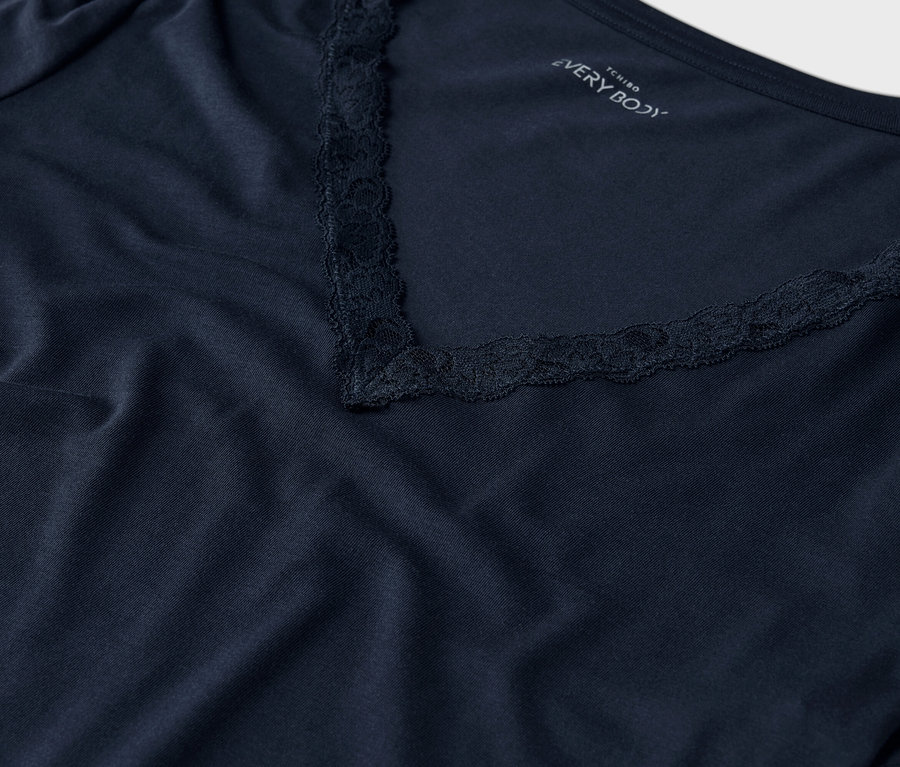 Gros plan d'un t-shirt bleu marine avec un col en V et des finitions en dentelle.