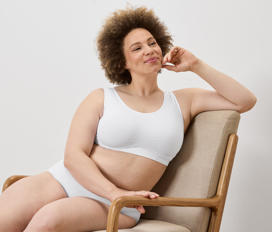 Femme avec afro assise dans un fauteuil en soutien-gorge et culotte blancs.
