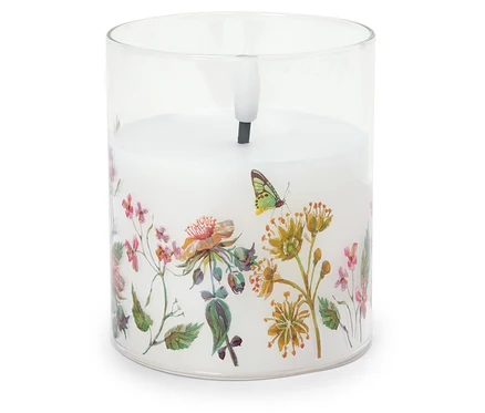 Bougie décorative dans un récipient en verre avec motif floral.