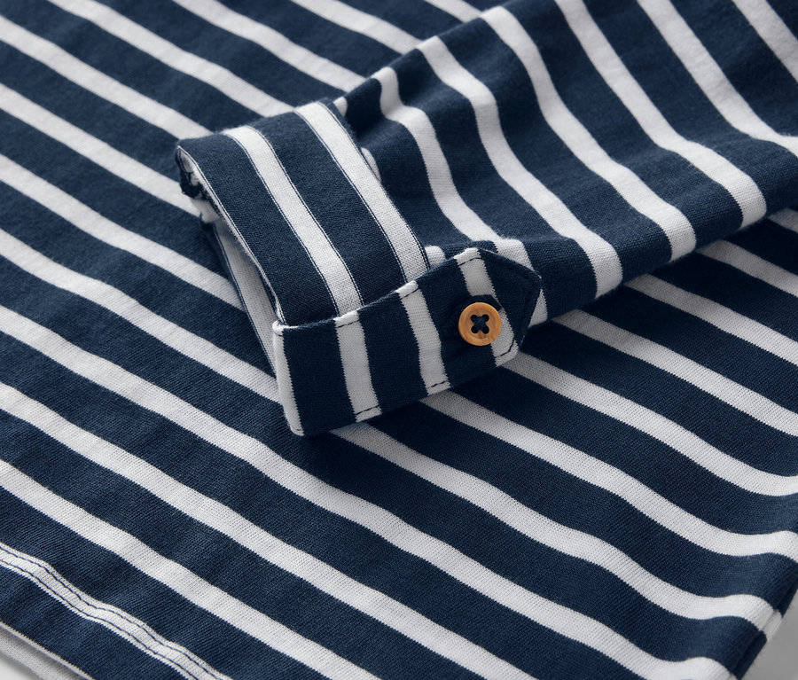 Gros plan sur un t-shirt à manches longues pour enfant, rayé bleu et blanc avec un bouton.