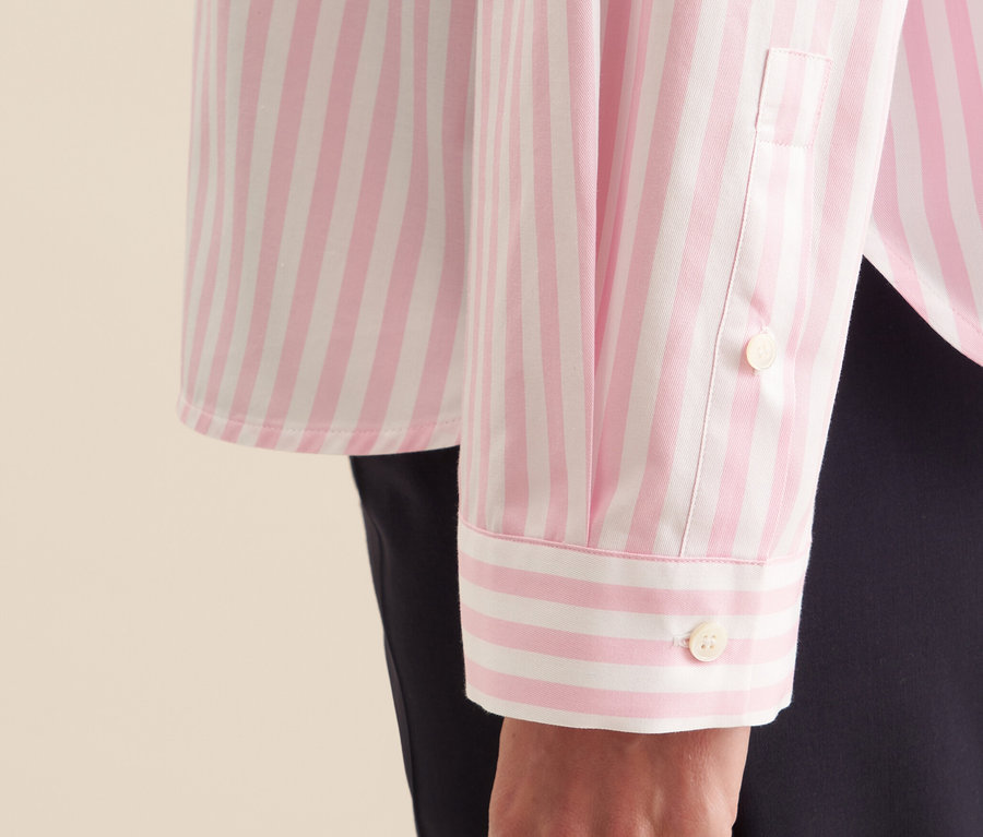 Gros plan sur une chemise oversize Seidensticker rose à rayures blanches, portée par une femme.