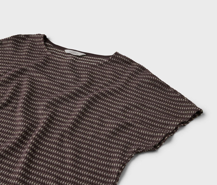 Gros plan d'un t-shirt marron à manches courtes avec un motif à pois clairs sur fond gris.