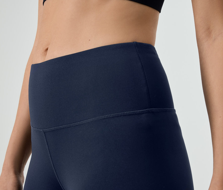 Gros plan d'une femme portant un legging bleu marine et un haut de sport noir.